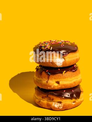 Tre ciambelle Boston Cream su sfondo giallo Foto Stock