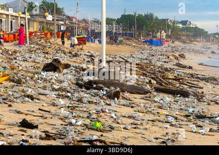 Bali, Indonesia - 22 dicembre 2024: La spiaggia è coperta di rifiuti e detriti, tra cui bottiglie di plastica e legno. La scena è caotica e poco attraente, con p Foto Stock