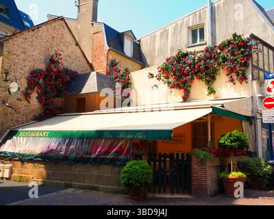 Affascinante ristorante francese con decorazioni floreali rosse nella luce soffusa del pomeriggio Foto Stock