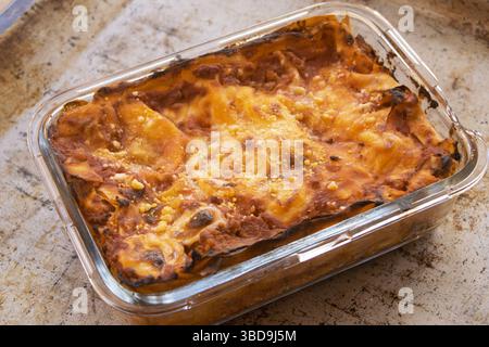 un tavolo rustico con spaghetti di grano intero, zucchine fresche e un vivace pomodoro rosso. Per un'alimentazione sana e concetti di cucina mediterranea. Foto Stock