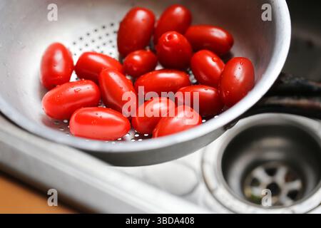 Pomodori rossi freschi in un filtro metallico. Primo piano nel lavandino della cucina. Verdure biologiche lavate. Preparazioni alimentari vegane salutari. Concetto di cucina quotidiana. Foto Stock