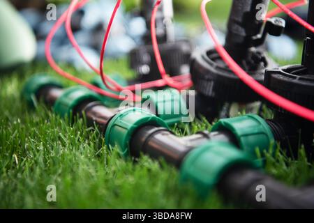 I componenti del sistema di irrigazione appena installati sono disposti su un prato verde rigoglioso. L'attenzione è rivolta ai tubi e alle valvole, mostrando la configurazione dettagliata per l'efficienza Foto Stock