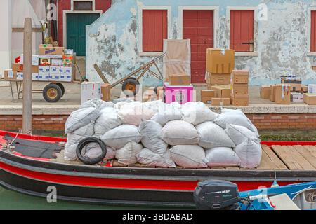 Venezia, Italia - 10 gennaio 2017: Consegna di merci sfuse in sacchi spedizione in barca sull'isola di Burano nel freddo giorno invernale. Foto Stock