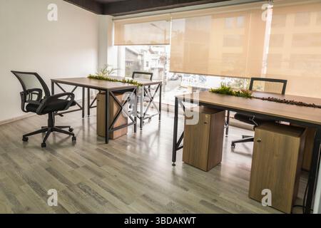 Una spaziosa sala riunioni con tavoli, sedie e una grande finestra che riempie lo spazio di luce naturale, creando un atmos luminoso e professionale Foto Stock