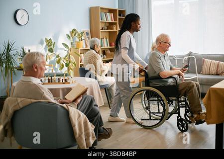 Infermiere che assiste gli anziani su sedia a rotelle Foto Stock