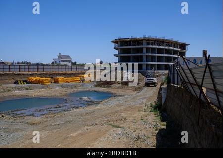 Escavatore che lavora vicino a una fossa di fondazione e una struttura parzialmente costruita a Cipro. Foto Stock