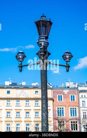 Storica Lanterna di strada con ornati lavori in ferro contro le colorate case a schiera in Polonia, marzo Foto Stock