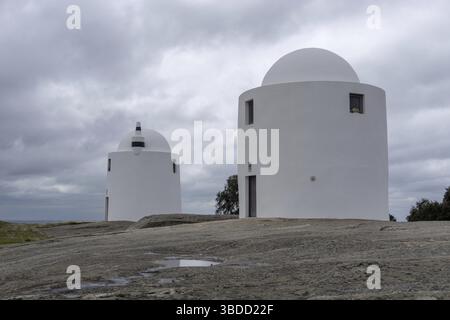 Evora, Portogallo - 24 marzo 2022: I mulini a vento di Sao Bento di Evora sotto un cielo sovrasparato espressivo Foto Stock