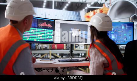Ingegneri che lavorano insieme nel laboratorio aerospaziale costruendo una nuova tecnologia satellitare. Foto Stock