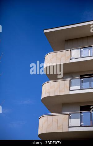 Il moderno design architettonico presenta balconi curvi splendidamente adagiati su un cielo azzurro Foto Stock
