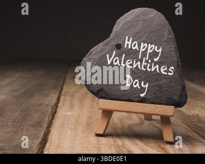 Forma del cuore di ardesia con le parole Happy San Valentino su un piccolo cavalletto in legno Foto Stock