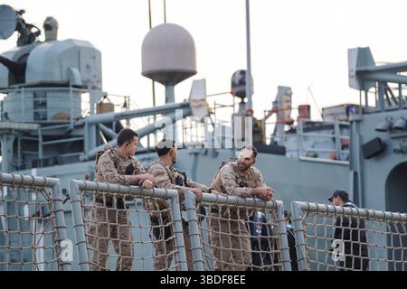 Spagna Malaga 1 28 2024 gruppo di militari in uniformi mimetiche su una nave navale all'alba del crepuscolo, impegnato in discussioni, assicurato dalla nave Foto Stock