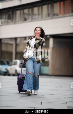 Giovane donna che cammina con gioia con i bagagli. Foto Stock