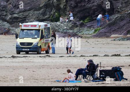 Polzeath, Cornovaglia, Regno Unito. 24 maggio 2025. Meteo nel Regno Unito: I turisti in banca affrontano le mutevoli condizioni di Polzeath, Cornovaglia. Nella foto: Persone che acquistano gelati da un pulmino sulla spiaggia sabbiosa di Polzeath, credito: Nidpor/Alamy Live News Foto Stock