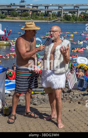 The Big Float, Portland, Oregon - 14 luglio 2018: Un uomo intervista un partecipante vestito con un gilet di pelliccia e una gonna all'evento annuale Big Float. Foto Stock