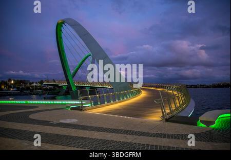 Moderno ponte pedonale illuminato al Dusk Reflecting Colors sulle acque calme di Elizabeth Quay, Perth, Australia, 14 aprile 2020 Foto Stock