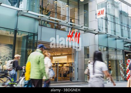 Negozio H&M con facciata in vetro e persone che camminano davanti Foto Stock