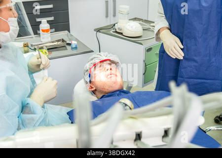 L'adolescente mostra insoddisfazione mentre sdraiato su una sedia dentale, preparandosi per i trattamenti dentali in una clinica Foto Stock