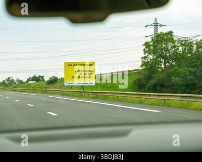 Francese, Francia - 24 agosto 2023: Vista da un'auto in movimento su un'autostrada francese, superando un cartello giallo che annuncia la ristrutturazione della strada tra luglio e S. Foto Stock