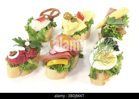Canape con insalata, formaggio, salsiccia, formaggio spalmabile e uova su sfondo bianco Foto Stock