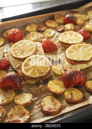 Filetto di merluzzo guarnito con timo, aglio e pomodori, preparazione di un piatto sano. Concetto di cibo sano Foto Stock