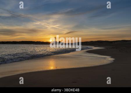 Tramonto tranquillo sulla spiaggia di Playa de Maria Sucia con Il faro di Cape Trafalgar sullo sfondo Foto Stock