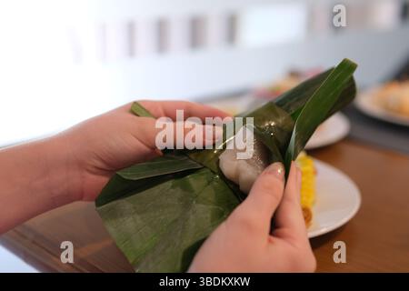 Torta tradizionale avvolta in foglie di banana a forma di cono, chiamata torta Mendut, ripiena di cocco grattugiato. Riprese 4K di alta qualità Foto Stock