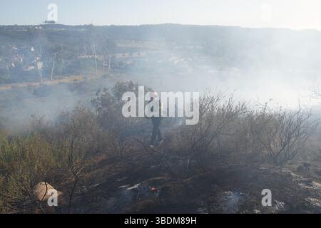 Poway, Stati Uniti. 24 maggio 2025. Un vigile del fuoco contiene il fuoco sulla montagna. Un incendio scoppiò nel pomeriggio del 24 maggio a Poway, contea di San Diego, California, bruciando circa quattro acri e provocando un ordine di evacuazione temporaneo. I vigili del fuoco di San Diego hanno risposto rapidamente, schierando almeno cinque camion dei vigili del fuoco e due elicotteri per contenere il fuoco. I vigili del fuoco sono stati in grado di fermare i progressi in avanti del fuoco e portarlo sotto controllo rapidamente. L'ordine di evacuazione è stato revocato più tardi quella sera. Credito: SOPA Images Limited/Alamy Live News Foto Stock