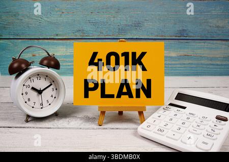 Testo del piano 401k scritto su carta con calcolatrice e sveglia su sfondo in legno Foto Stock