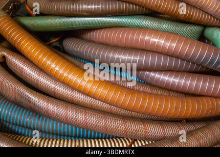 Un mucchio di tubi flessibili in plastica con una treccia metallica all'interno, primo piano. Foto Stock