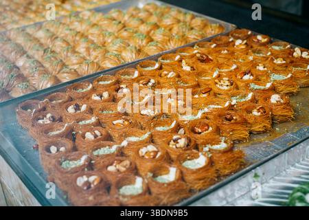 Dolcetti baklava appena sfornati esposti in una pasticceria Foto Stock