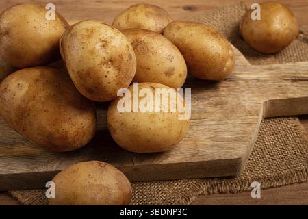 Patate crude, sparse su un tagliere, primo piano, nessuna gente Foto Stock