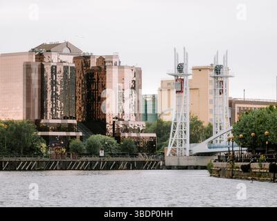 Salford, Manchester, Regno Unito, 05-24-2025: Moderna architettura lungo il fiume con edifici riflettenti e strutture di ponti. Foto Stock