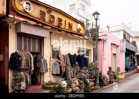 KIN Town liegt an der Ostküste der Insel Okinawa in Giappone und ist bekannt für Seine einzigartige Mischung aus traditioneller Kultur, militärischer Präsenz und kulinarischer Innovation. Die Nähe zu Camp Hansen, einem US-Marine-Stützpunkt, prägte die Stadt über Jahrzehnte hinweg. In den 1960er und 1970er Jahren War Kin Town besonders im Bereich Shinkaichi ein florierendes Unterhaltungszentrum mit bar, club e ristoranti, Die hauptsächlich US-Soldaten als Kunden hatten - heute kämpft die Stadt mit dem demografischen Wandel. KIN, 12.05.2025 Okinawa Giappone *** la città di Kin si trova nella parte est del coa Foto Stock