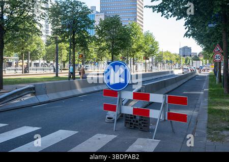 Lavori stradali nel centro della città, corsia chiusa con barricate, segnali stradali deviati ed edifici dall'architettura moderna Foto Stock