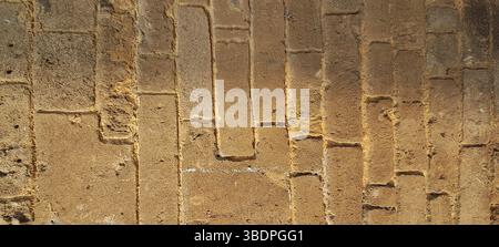 Sfondo testurizzato di una vecchia parete in mattoni di arenaria, che mostra agenti atmosferici, erosione e decadimento, adatto per sfondi e trame Foto Stock