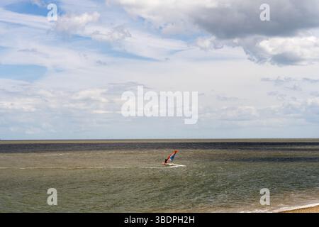 Swale Sittingbourne, Regno Unito. 25 maggio 2025. Tempo nel Regno Unito: Domenica soleggiata lungo la costa del Kent: Con una leggera brezza in aria, i windsurf si tuffano in acqua su tavole a vela mentre gli amanti della spiaggia si crogiolano nel calore del sole pomeridiano. Un vivace mix di relax e avventura mentre la scena costiera prende vita Credit: xiu bao/Alamy Live News Foto Stock