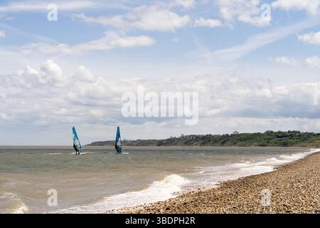 Swale Sittingbourne, Regno Unito. 25 maggio 2025. Tempo nel Regno Unito: Domenica soleggiata lungo la costa del Kent: Con una leggera brezza in aria, i windsurf si tuffano in acqua su tavole a vela mentre gli amanti della spiaggia si crogiolano nel calore del sole pomeridiano. Un vivace mix di relax e avventura mentre la scena costiera prende vita Credit: xiu bao/Alamy Live News Foto Stock