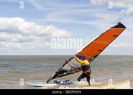 Swale Sittingbourne, Regno Unito. 25 maggio 2025. Tempo nel Regno Unito: Domenica soleggiata lungo la costa del Kent: Con una leggera brezza in aria, i windsurf si tuffano in acqua su tavole a vela mentre gli amanti della spiaggia si crogiolano nel calore del sole pomeridiano. Un vivace mix di relax e avventura mentre la scena costiera prende vita Credit: xiu bao/Alamy Live News Foto Stock