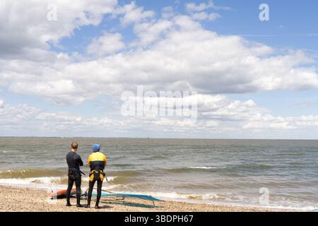 Swale Sittingbourne, Regno Unito. 25 maggio 2025. Tempo nel Regno Unito: Domenica soleggiata lungo la costa del Kent: Con una leggera brezza in aria, i windsurf si tuffano in acqua su tavole a vela mentre gli amanti della spiaggia si crogiolano nel calore del sole pomeridiano. Un vivace mix di relax e avventura mentre la scena costiera prende vita Credit: xiu bao/Alamy Live News Foto Stock