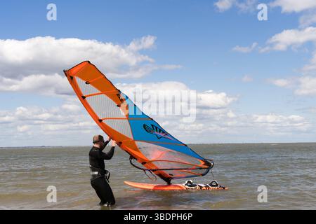 Swale Sittingbourne, Regno Unito. 25 maggio 2025. Tempo nel Regno Unito: Domenica soleggiata lungo la costa del Kent: Con una leggera brezza in aria, i windsurf si tuffano in acqua su tavole a vela mentre gli amanti della spiaggia si crogiolano nel calore del sole pomeridiano. Un vivace mix di relax e avventura mentre la scena costiera prende vita Credit: xiu bao/Alamy Live News Foto Stock