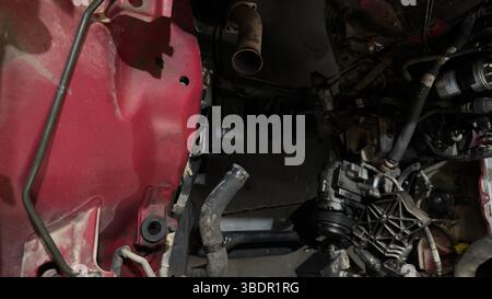 Vano motore per auto smontato con tubi flessibili e parti meccaniche visibili Foto Stock