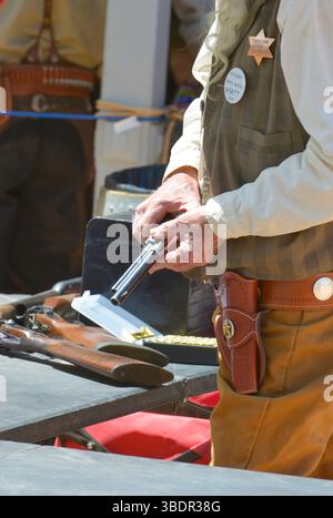 Cowboy Reenactor ricaricando il suo colt 45 per le strade di Tombstone, Arizona Foto Stock