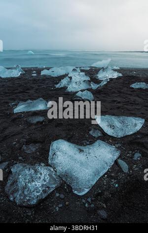 Diamond Beach in Islanda con blocchi di ghiaccio su Black Sand e una luce magica soffusa Foto Stock