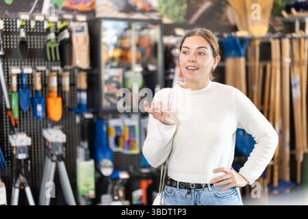 Giovane donna che sceglie gli attrezzi per il giardino Foto Stock