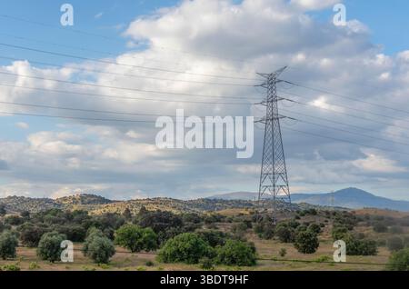 Linea elettrica ad alta tensione in mezzo alla campagna, tagliata contro un cielo spettacolare pieno di nuvole vorticose Foto Stock