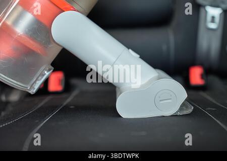 Aspirapolvere senza fili portatile per aspirare i rivestimenti dei sedili per auto. Pulizia e manutenzione degli interni delle auto moderne Foto Stock