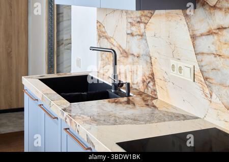 Un'elegante cucina con eleganti ripiani in marmo e un elegante design moderno del rubinetto Foto Stock