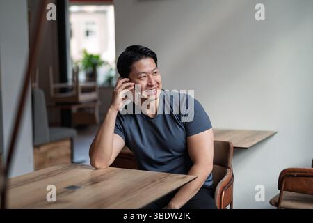 Uomo sicuro di sé che ha telefonato al tavolo del bar. Foto Stock