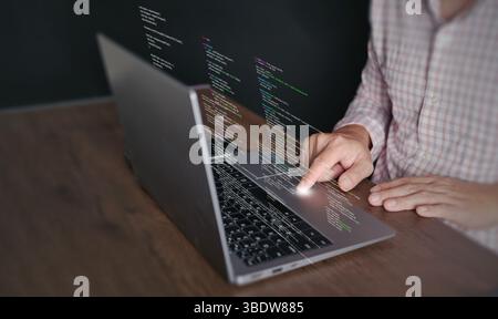Le mani di un programmatore digitano su un laptop visualizzando il codice di programmazione, simboleggiando la tecnologia di codifica, lo sviluppo di software, le applicazioni Web. Soluzioni IT, AN Foto Stock